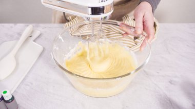 Adım adım. Vanilyalı Mardi Gras kekleri pişirmek için karışımı elektrikli mikserle karıştırıyorum..