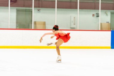 Genç kız buz pateni pistinde artistik patinaj yapıyor..