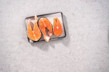 Düz yatıyordu. Parşömen kağıdıyla pişirme tepsisinde çiftlik somonu bifteği..