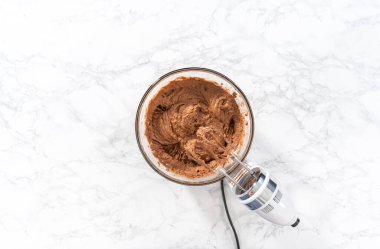 Düz yatıyordu. Büyük bir bardakta ıslak malzemeler karıştırarak kırmızı kadife kekler ve beyaz çikolatalı ganache kreması pişiriyorum..