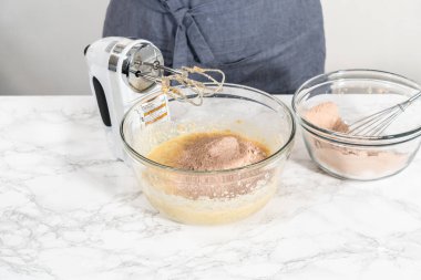 Büyük bir bardakta ıslak malzemeler karıştırarak kırmızı kadife kekler ve beyaz çikolatalı ganache kreması pişiriyorum..