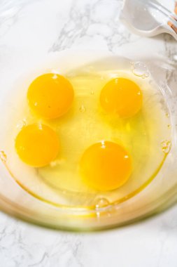 Büyük bir bardakta ıslak malzemeler karıştırarak kırmızı kadife kekler ve beyaz çikolatalı ganache kreması pişiriyorum..