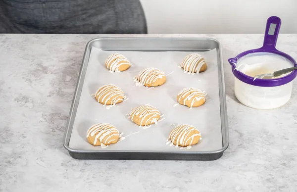 Drizzling melted white chocolate over freshly baked eggnog scones.