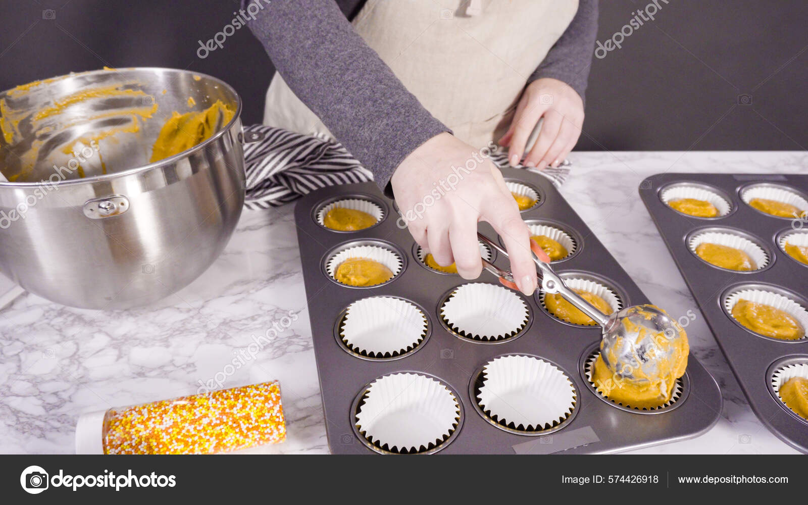 Premium Photo  Scooping pumpkin spice cupcake batter with batter scoop  into a cupcake pan with liners.