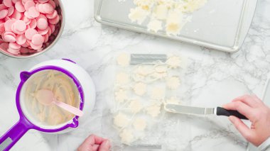 Düz yatıyordu. Adım adım. Erimiş çikolatayı kar taneleri şeklinde plastik bir çikolata kalıbına döküyorum..