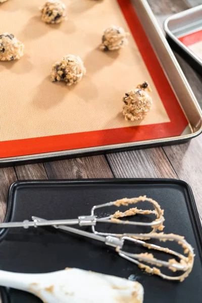 Scoops of cookie dough on a baking cheets to bake chewy oatmeal raisin cookies.