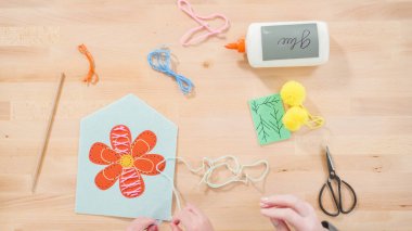 Küçük kız annesiyle el sanatları masasında dikiş dikmeyi öğreniyor..