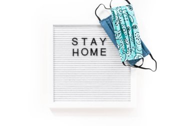 İleti panosunda ev yapımı yüz maskesi ile Ev Kal tabelası.