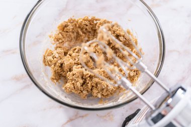 Elmalı yulaflı kurabiye pişirmek için büyük bir bardakta karıştırma malzemesi..