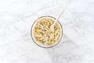 Düz yatıyordu. Makarna salatasını tavukla karıştırmak için büyük bardakta malzemeler karıştırıyorum..