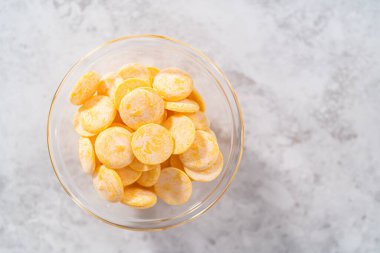 Mutfak tezgahındaki küçük cam kasede sarı çikolata parçaları..