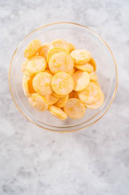 Mutfak tezgahındaki küçük cam kasede sarı çikolata parçaları..