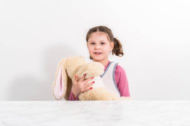 Paskalya yumurtası boyası. Küçük kız doldurulmuş tavşancığına sarılıyor.