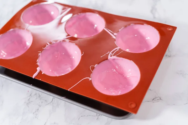 用融化的粉红巧克力填充硅胶巧克力模子 准备热巧克力炸弹 — 图库照片