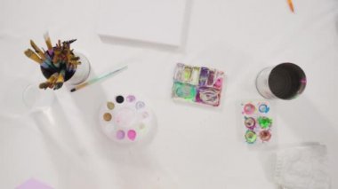 Evde akrilik boyalı bir sanat projesi üzerinde çalışan küçük bir kız..