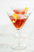 Cosmopolitan koktejl v martini sklenici a zdobený citrónovým vírem.