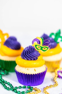 Mardi Gras vanilyalı kekler folyo kaplarda ve İtalyan tereyağlı kremayla süslenmiş..