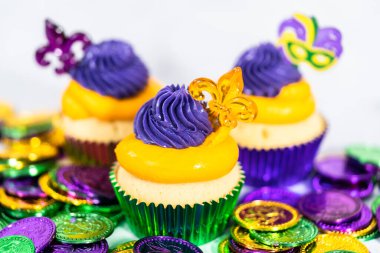 Mardi Gras vanilyalı kekler folyo kaplarda ve İtalyan tereyağlı kremayla süslenmiş..