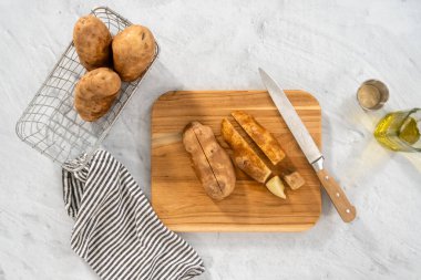 Düz yatıyordu. Fırında pişirmek için ahşap kesme tahtasıyla russet patateslerini dilimlemek..