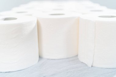 Gri arka planda yeni beyaz tuvalet kağıdı ruloları.