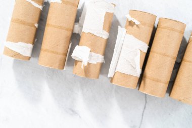 Gri arkaplanda boş tuvalet kağıdı ruloları kullanılıyor.