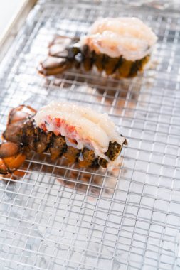 Çiğ ıstakoz kuyrukları mutfak folyosuyla fırında pişirilmeye hazır..