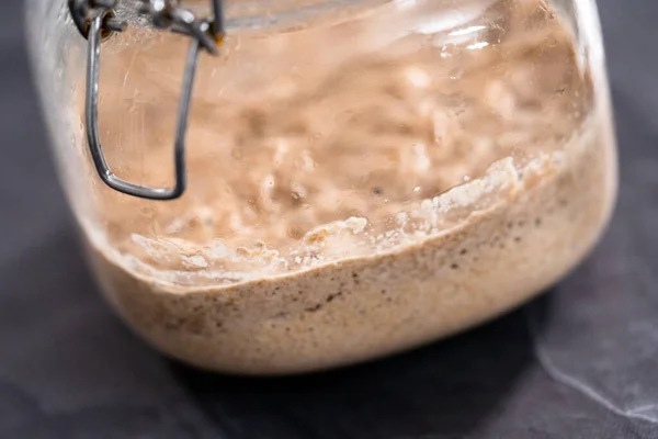 Homemade wheat sourdough starter in a glass mason jar.