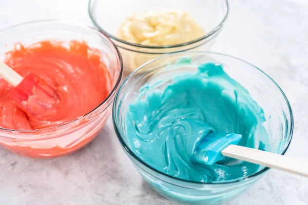Mixing red and blue food coloring into the cake dough.