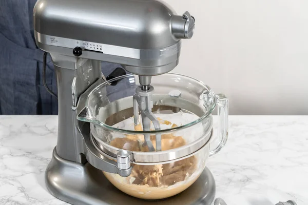 Mixing ingredients in a kitchen stand mixer to bake soft oatmeal raisin walnut cookies.