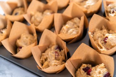 Kızılcık keki pişirmek için hamur toplarını kek bardaklarına dolduruyorlar..