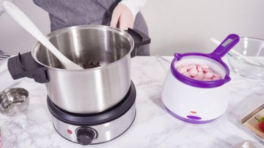 Adım adım. Çikolata parçacıkları eriyen kaplarda eriyor..