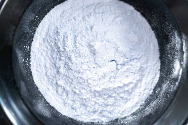 Siyah plastik bir kasede beyaz arka planda saç boyası tozu..