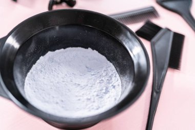 Siyah plastik bir kasede pembe arka planda saç boyası tozu..
