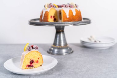 Dilimlenmiş limonlu kek. Şeker kızılcıkları ve limon dilimleri ile süslenmiş..