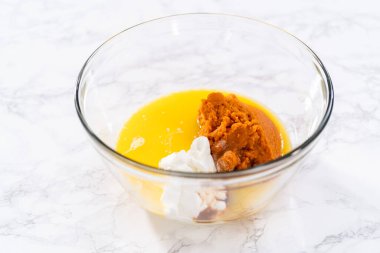 Büyük bir bardakta karıştırılan malzemeler kabaklı kek yapmak için karıştırılıyor..