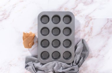 Düz yatıyordu. Sharlotka çörekleri pişirmek için parşömen kağıtlarıyla kaplanmış kek tavasına hamur atıyorlar..