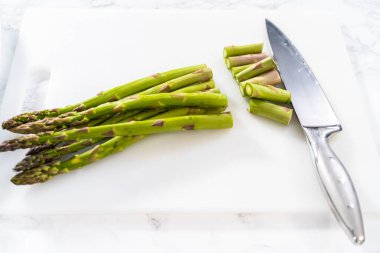 Beyaz bir kesme tahtasıyla taze kuşkonmaz kesiyorum..