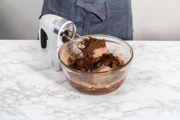 Mixing ingredients with a hand mixer to bake chocolate cookies with chocolate hearts for Valentine\'s Day.