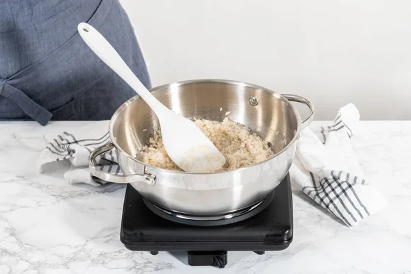 Cooking Mexican rice in a stainless steel cooking pot.