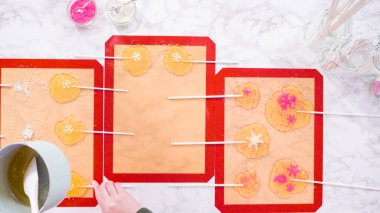 Düz yatıyordu. Ev yapımı lolipoplar yapmak için silikon paspaslara karamelize şeker dökmek..