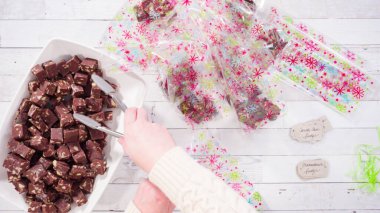 Düz yatıyordu. Adım adım. Ev yapımı macadamia şekerlemesi küçük hediye paketlerine konuyor..