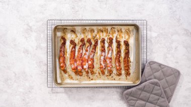 Düz yatıyordu. Adım adım. Beyaz parşömen kağıdıyla pişirilmiş pastırma şeritleri..