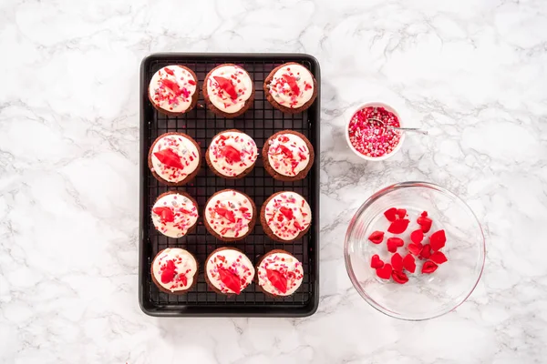 Flat lay. Flat lay. Red velvet cupcakes with cream cheese frosting and decorates with heart and kiss shaped red chocolates.