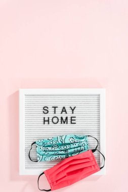 İleti panosunda ev yapımı yüz maskesi ile Ev Kal tabelası.