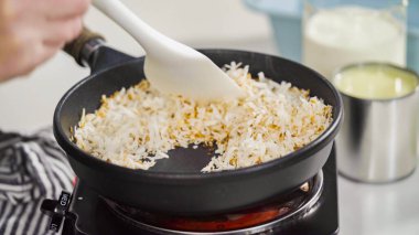 Ev yapımı hindistan cevizli dondurma hazırlamak için kızartma tavasında hindistan cevizi gevreği..