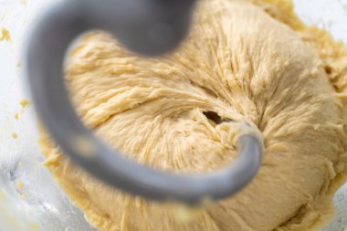 Ev yapımı brioche çörekleri pişirmek için mutfak mikserindeki malzemeleri karıştırıyorum..