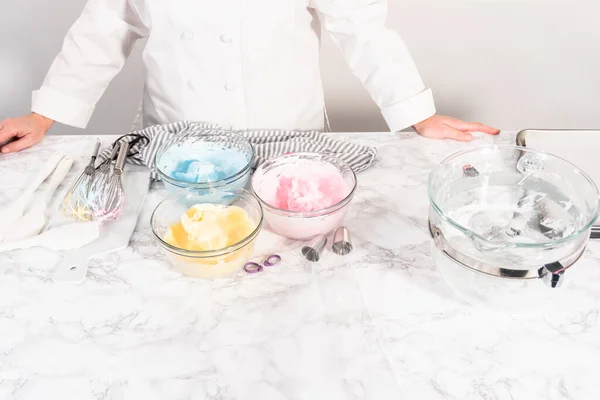 Mixing food coloring into the meringue to bake unicorn meringue cookies.