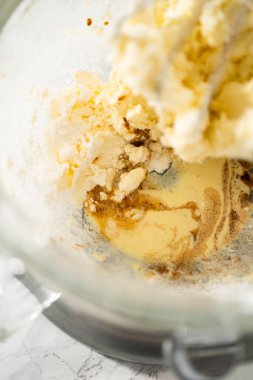 Büyük bir bardaktaki malzemeleri karıştırıyorum. Yumurta likörü kreması yapmak için mutfak mikserini karıştırıyorum..