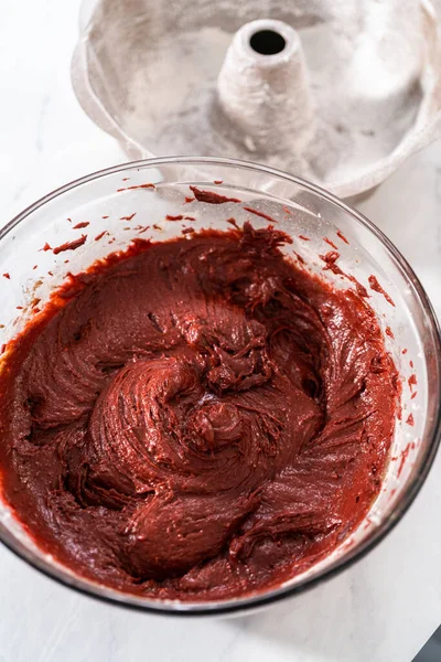 Filling metal bundt cake pan with cake butter to bake red velvet bundt cake with cream cheese glaze