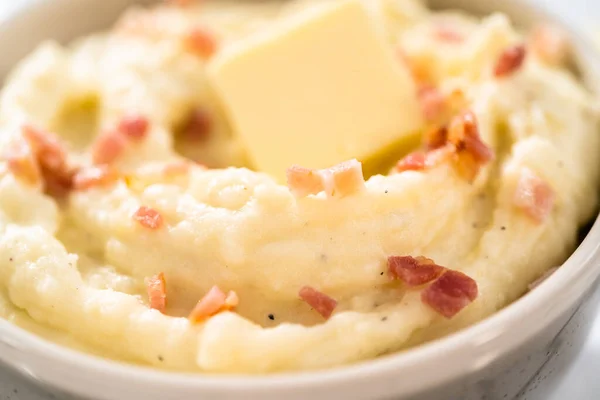 Mashed potatoes. Creamy mashed potatoes garnished with a slice of butter and bacon bits in a bowl.